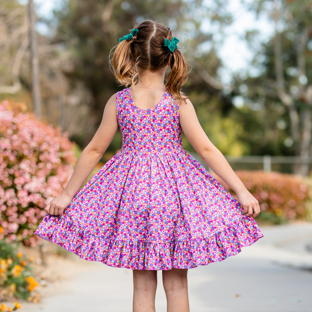 back detail of purple floral dress on little girl wearing pigtails