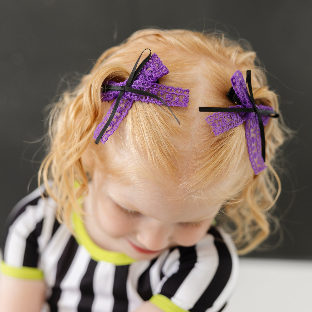 little girl in purple lace pigtail bows with black ribbon detail paired with black and white striped Beetlejuice inspired tee