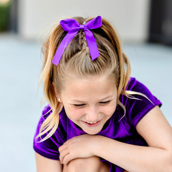 little girl in purple satin ribbon bow paired with matching purple velvet top and skort for Halloween