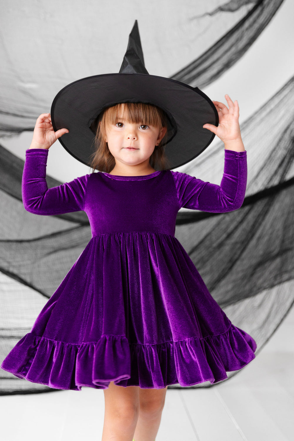 little girl wearing purple velvet dress and witch hat for halloween