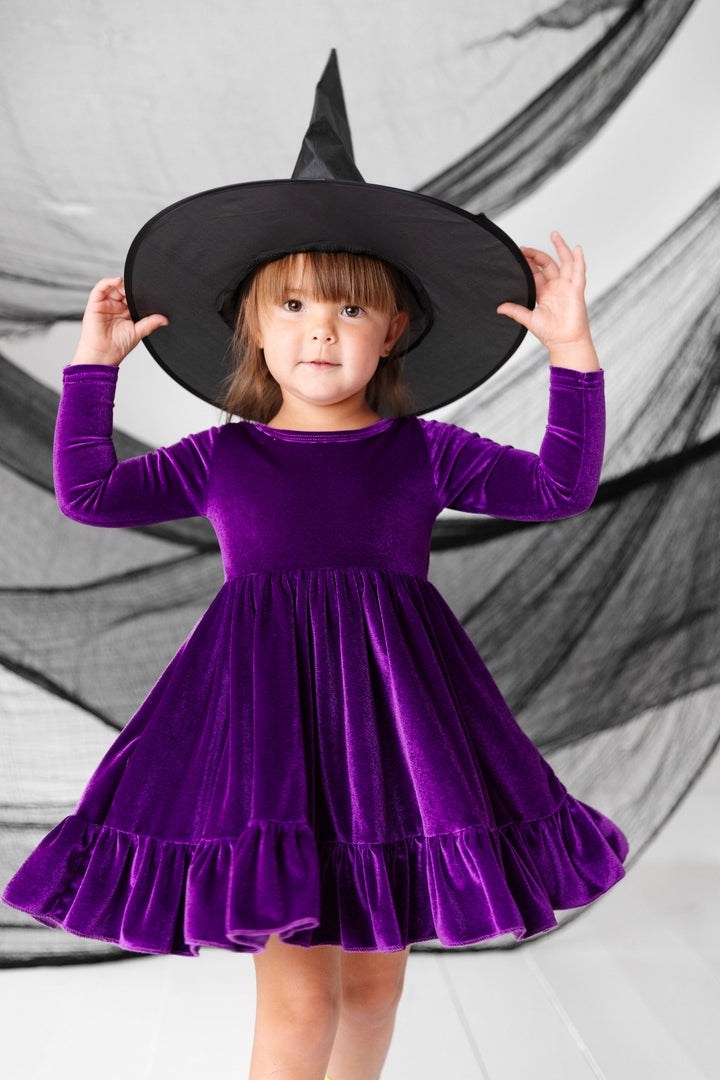 little girl wearing purple velvet dress and witch hat for halloween