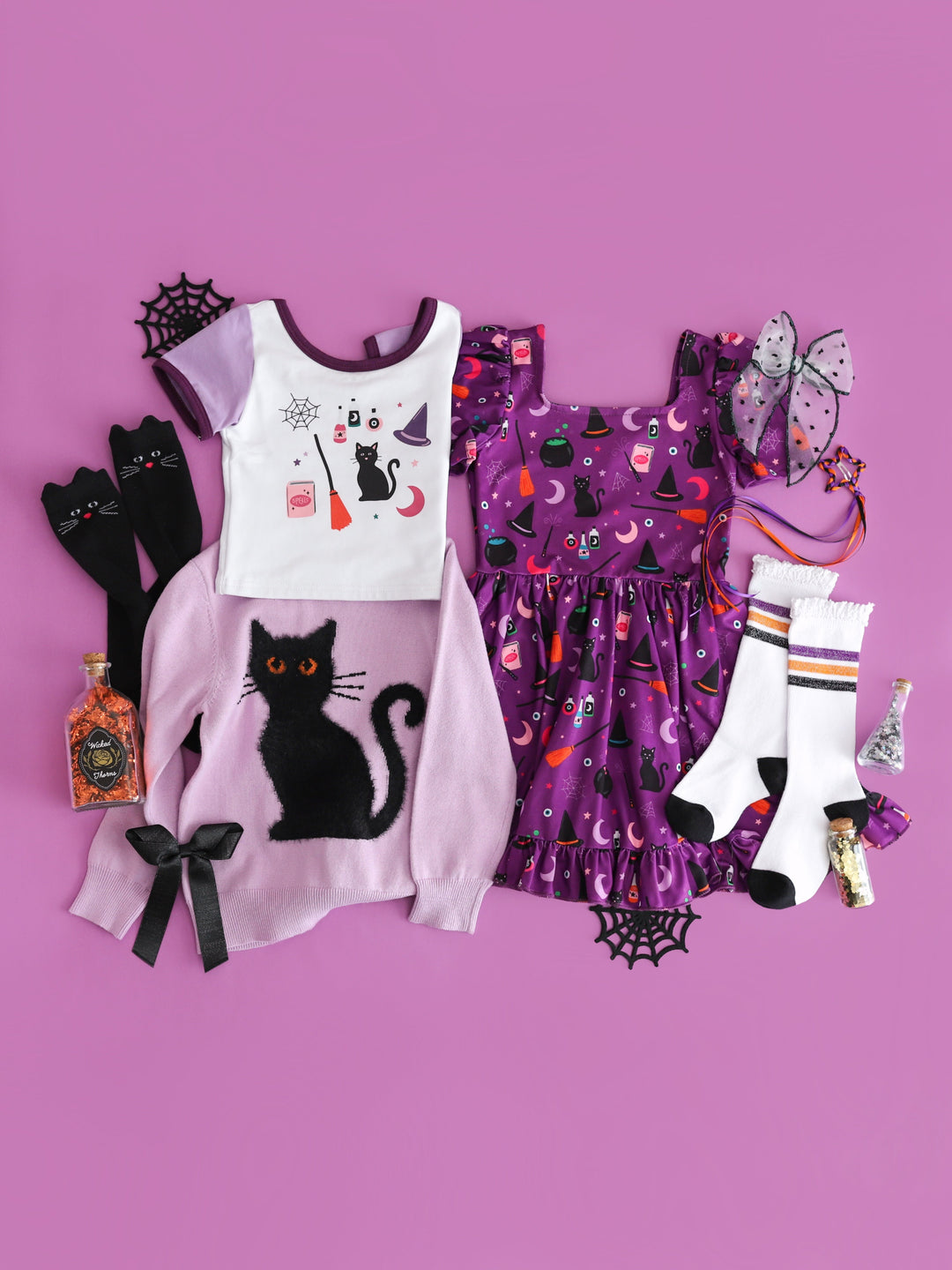 flat lay inspiration featuring dress and fitted top in witchy themed prints with matching lavender sweater with fluffy black cat and coordinating accessories 
