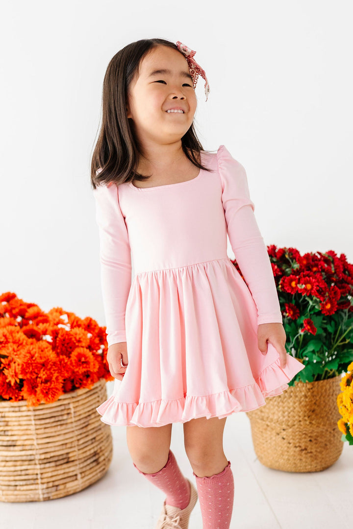 little girl wearing light pink long sleeve dress with knee high socks
