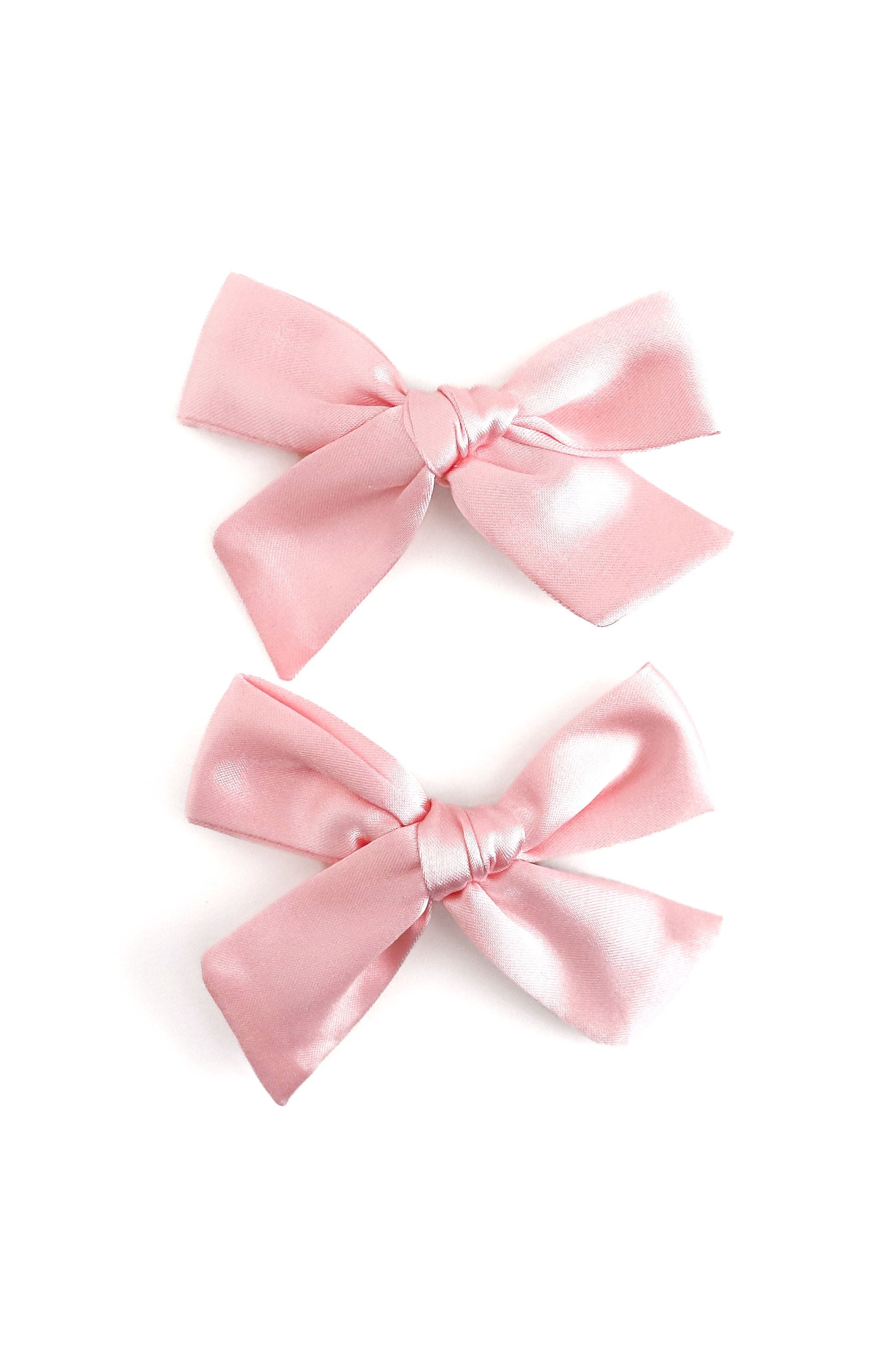 Two light pink satin bows arranged vertically on a clean white background.