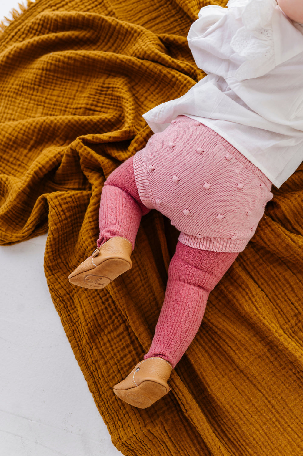 baby girl on blanket in pink knit bubble bloomers paired with pink cable knit tights