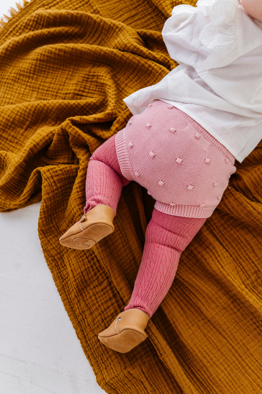 baby girl on blanket in pink knit bubble bloomers paired with pink cable knit tights