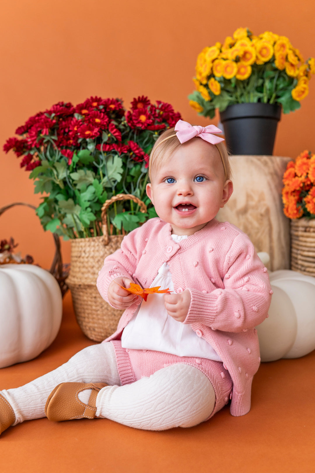 baby girl holding fall leaf in pink button front cardigan with bubble design paired matching bloomers and white cable knit tights