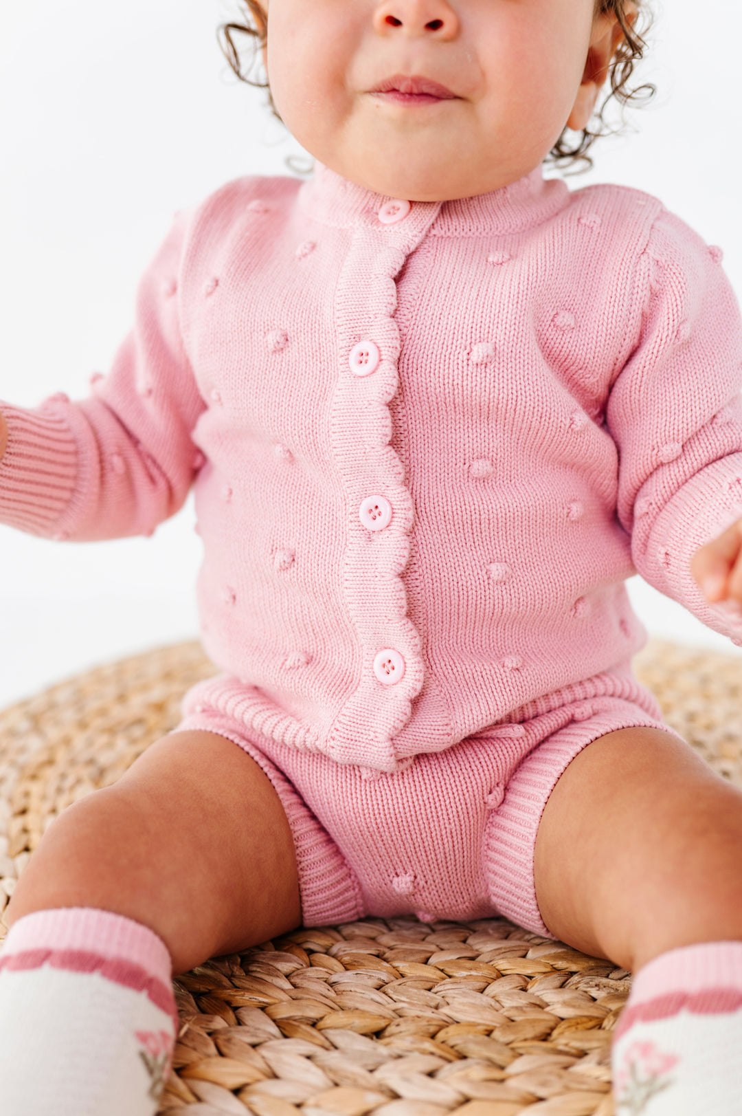 closeup of pink button front cardigan with bubble design and matching bubble bloomers on baby girl 