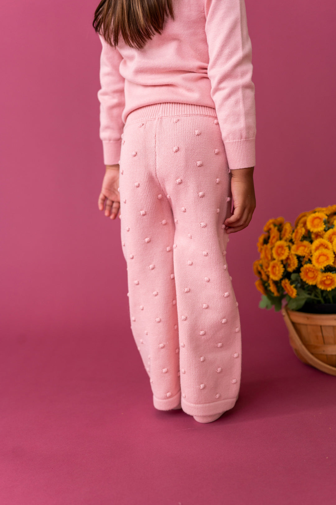 back view of little girl wearing pink sweater pants with bubble texture 