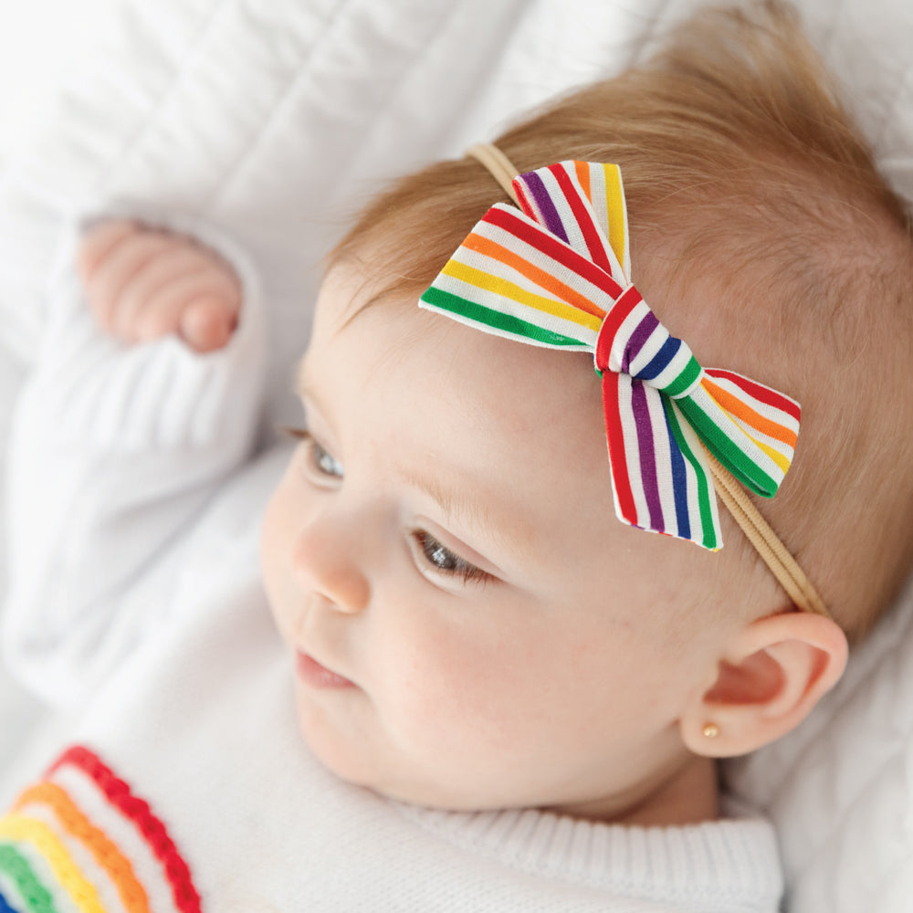 baby girl wearing rainbow stripe bow on nylon stretchy band
