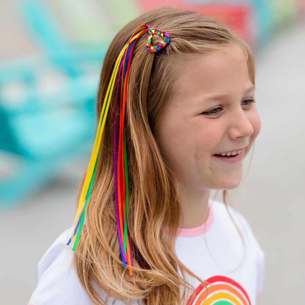 girl wearing rainbow braided heart shaped hair clip with ribbons for pride day