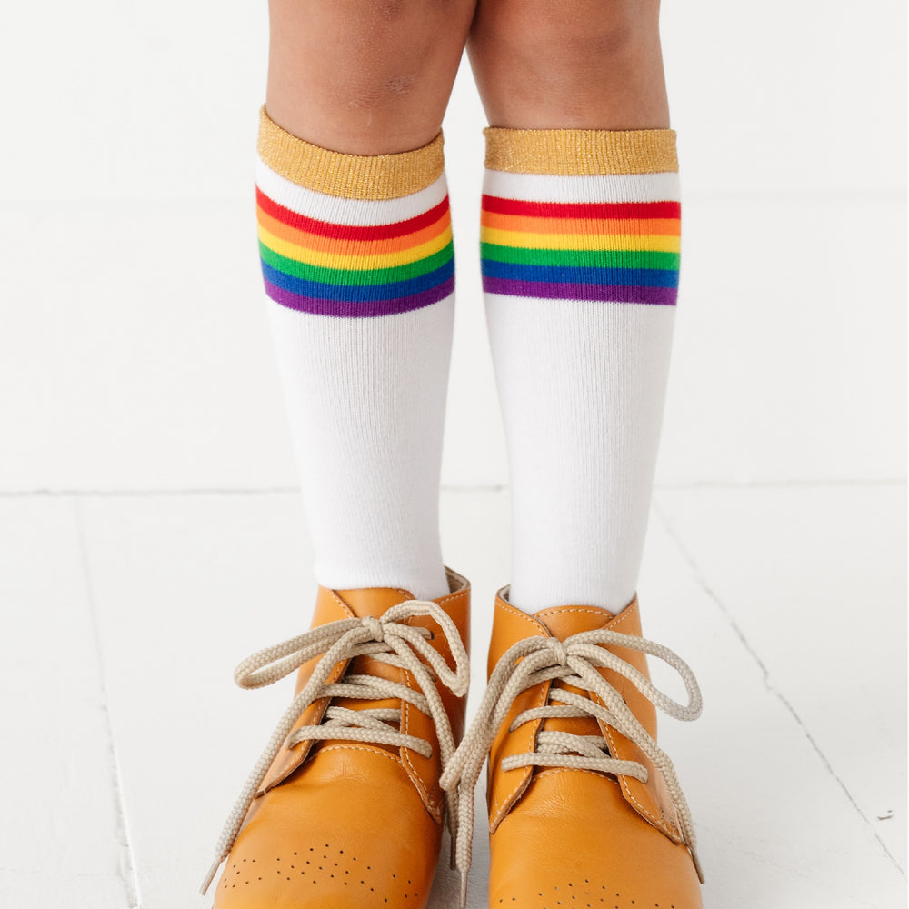 girl wearing white knee high sock with rainbow stripes and sparkly gold band