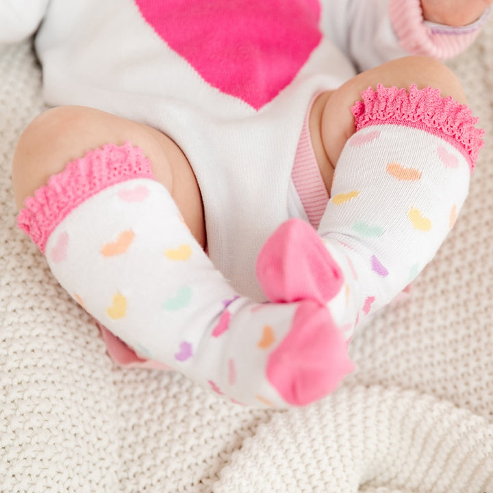 baby girl wearing rainbow heart knee high socks with pink lace