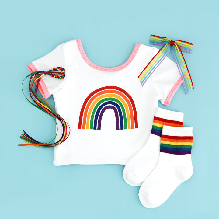 flat lay of white fitted tee with pink binding and rainbow design with matching rainbow socks and bow options for pride day