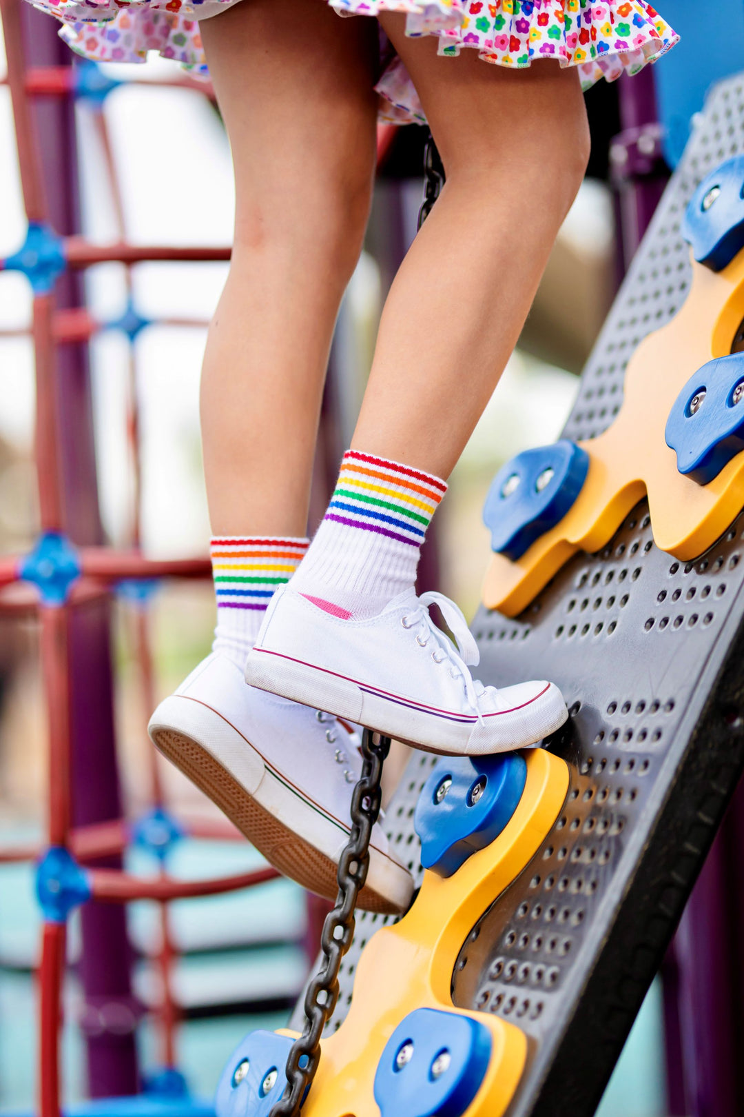 young girl climbing playground in crew socks with rainbow stripes at ankle