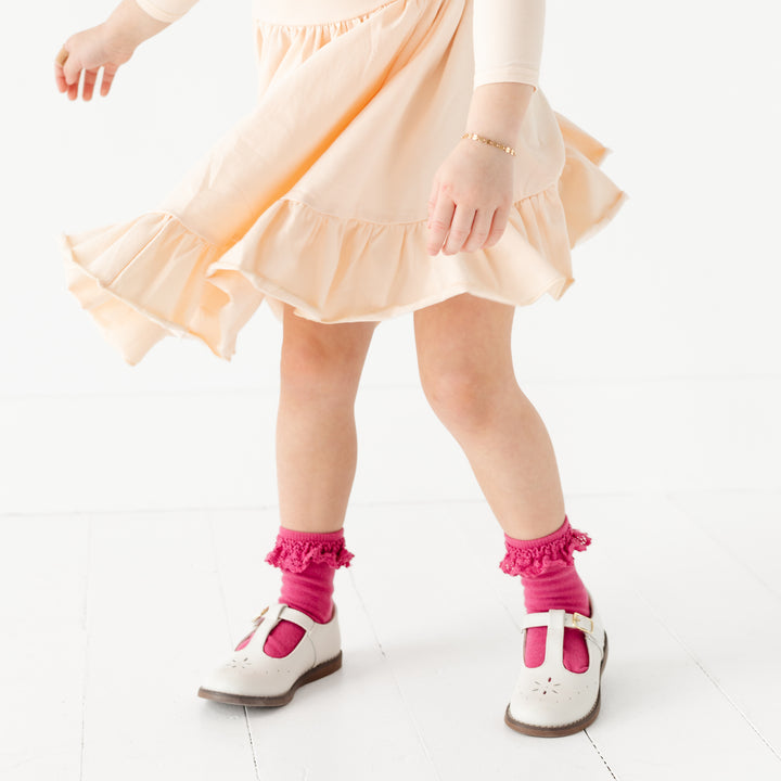 little girl twirling in vanilla pocket dress with cute raspberry pink lace trimmed midi socks
