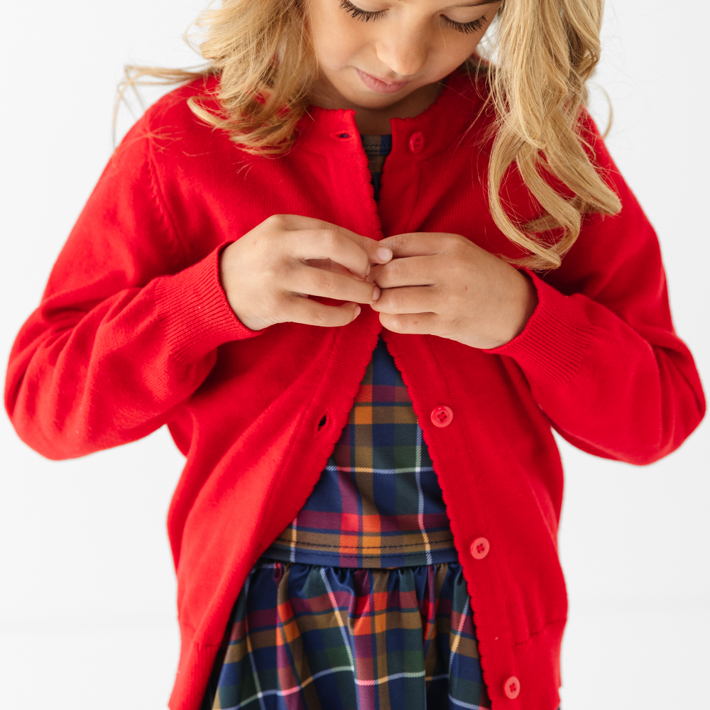 girl buttoning red cotton knit cardigan sweater with button front for school uniform and back to school outfits