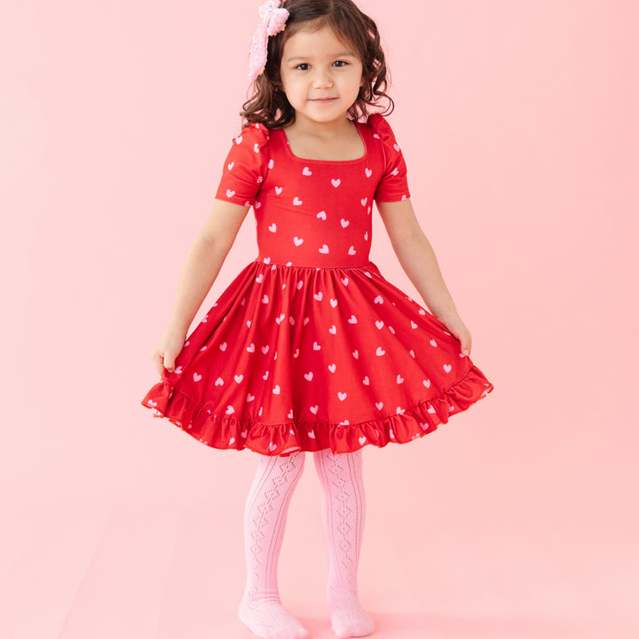 girl in square neck red dress with pink hearts on it and pink fancy crochet tights