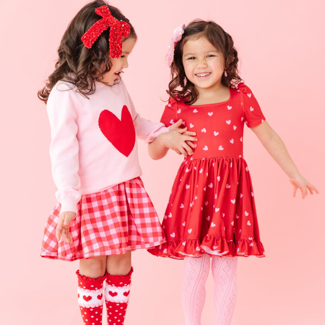 twin girls in matching red and pink heart valentines outfits