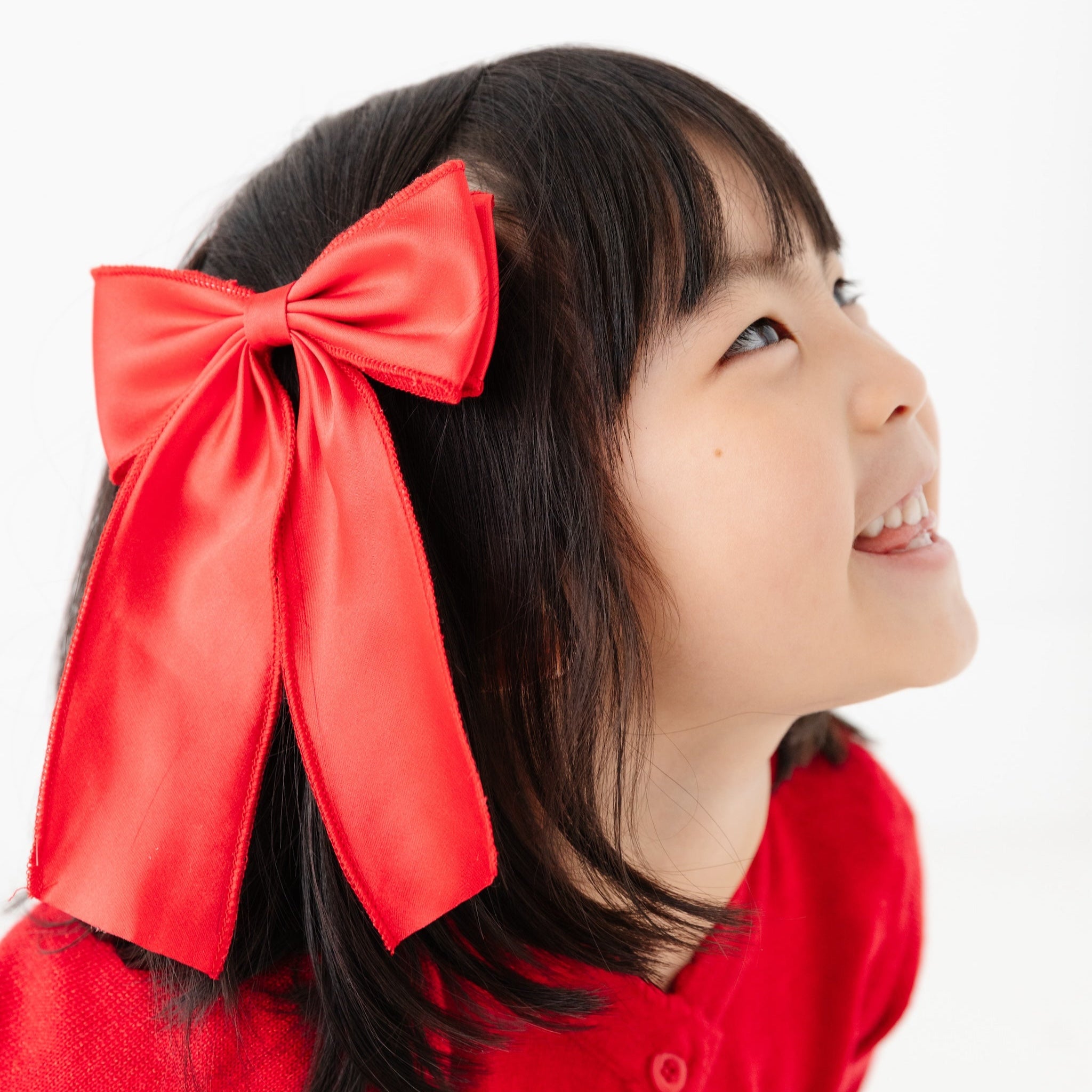 young girl in oversized bright red satin double bow on clip for Christmas