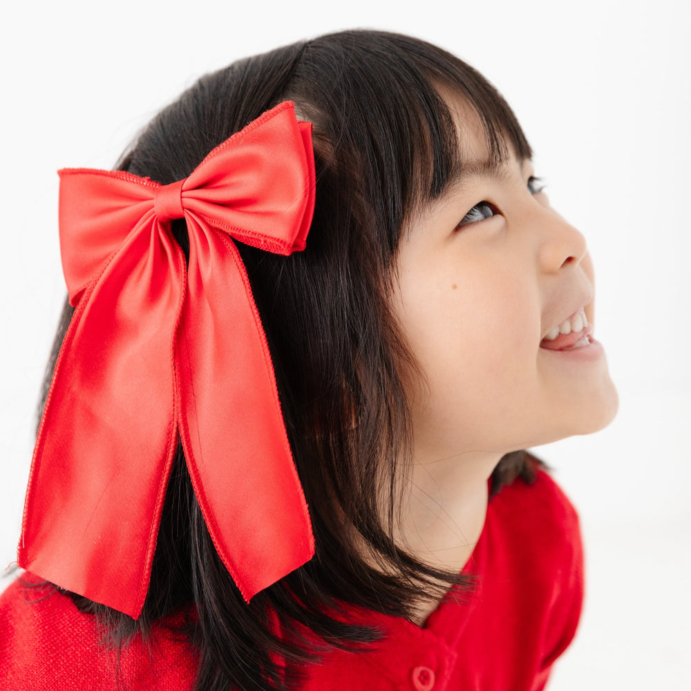 young girl in oversized bright red satin double bow on clip for Christmas
