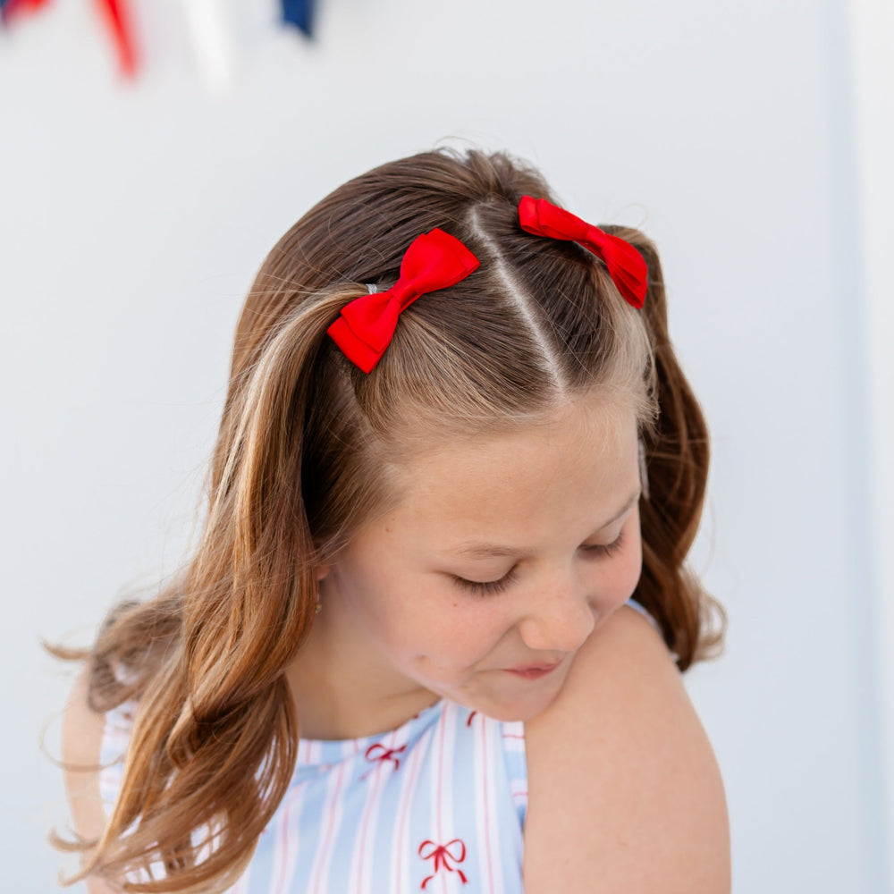 little girl in 4th of july bow dress with matching bright red satin pigtail bows on clips