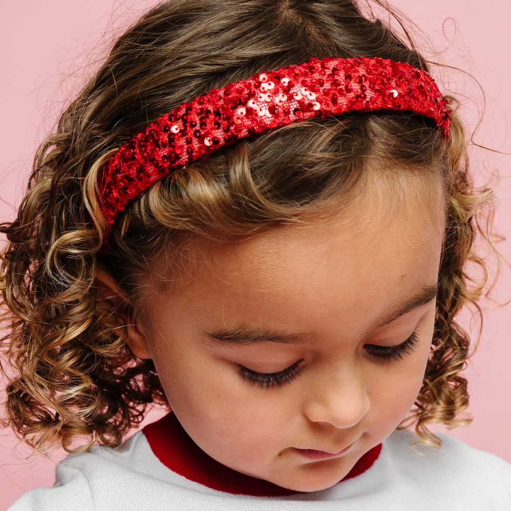 little girl in red sequin headband and matching red and white sweater for christmas
