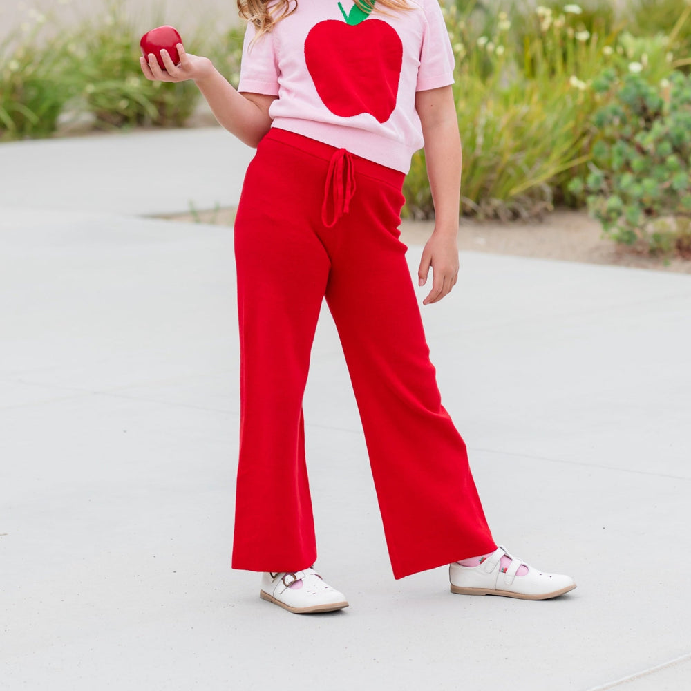 girl wearing red cotton sweater pants with drawstring and matching pink sweater with red apple