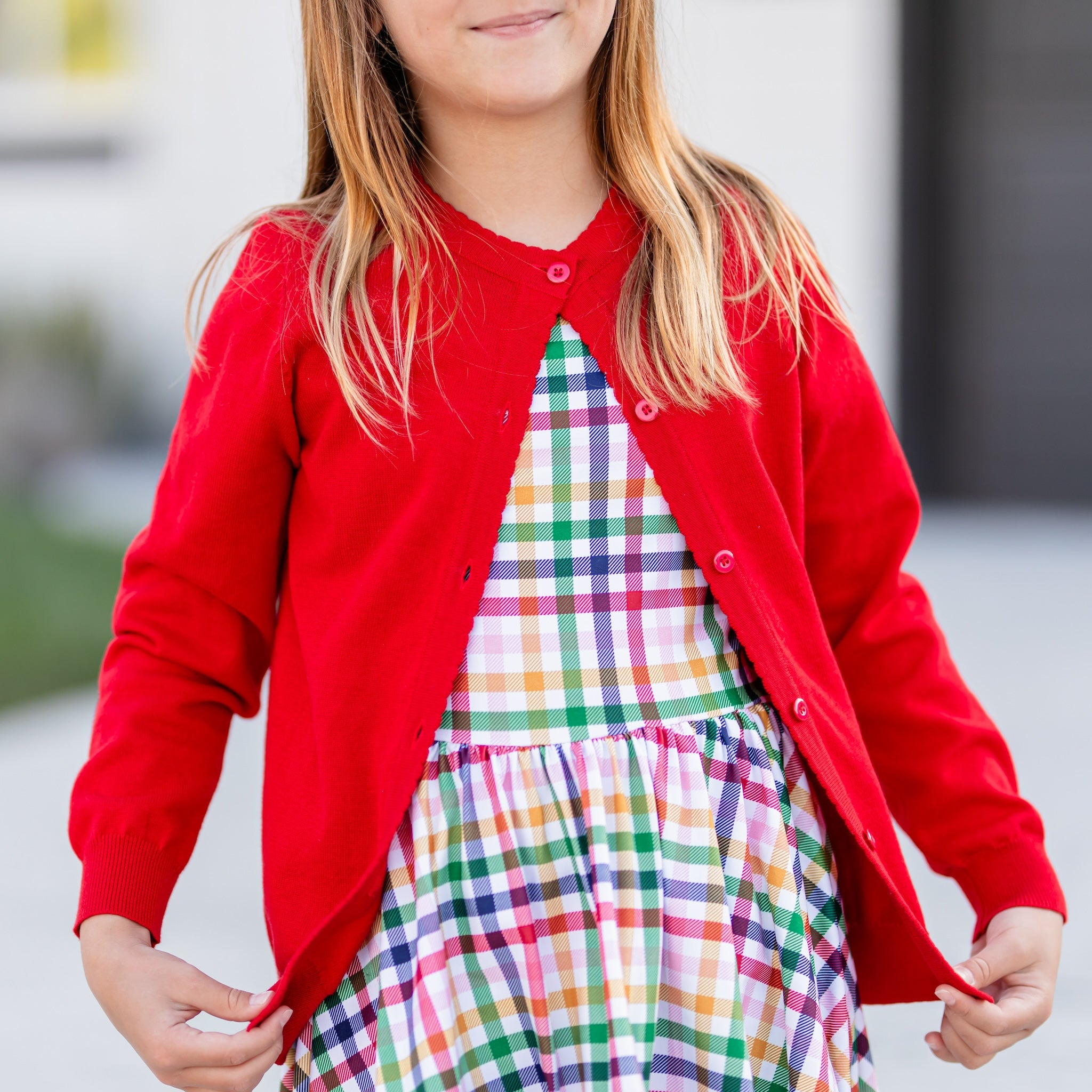 girl wearing back to school rainbow gingham twirl dress with matching red cotton button up cardigan with scallop trim