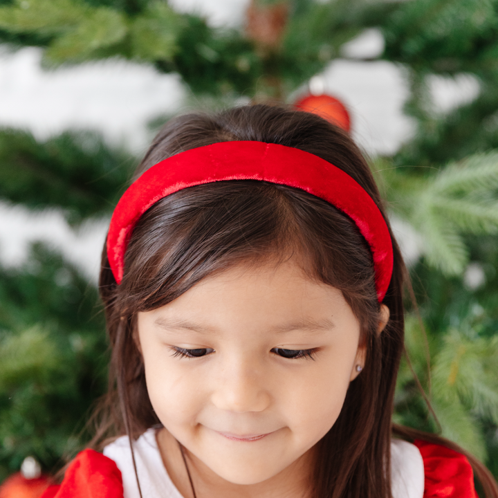 little girl in front of Christmas tree in bright red velvet padded headband