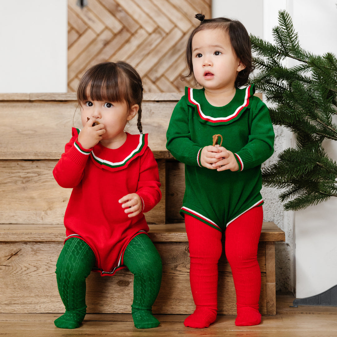 two toddler girls in red and green sweater rompers with matching red and green cable knit tights