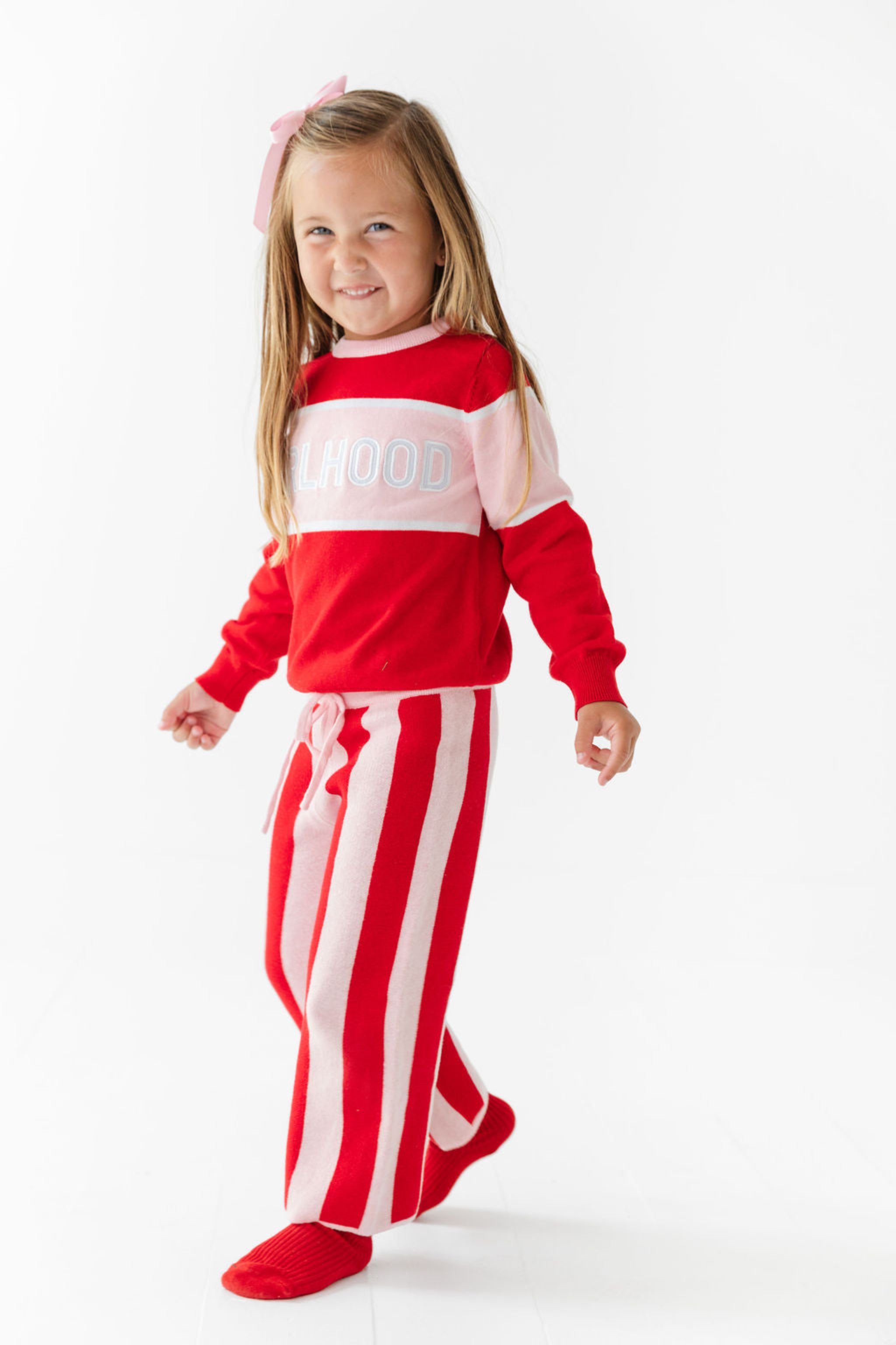 little girl in red and pink knit sweater with Girlhood design and matching red and pink sweater pants