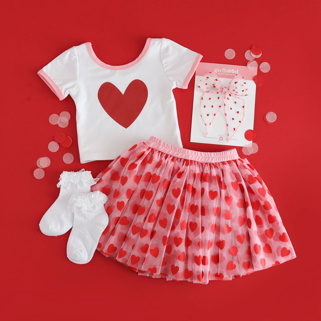 girls red and pink Valentine's outfit with red heart top paired with pink and red tulle skort, white lace bobby socks and matching sheer hair bow