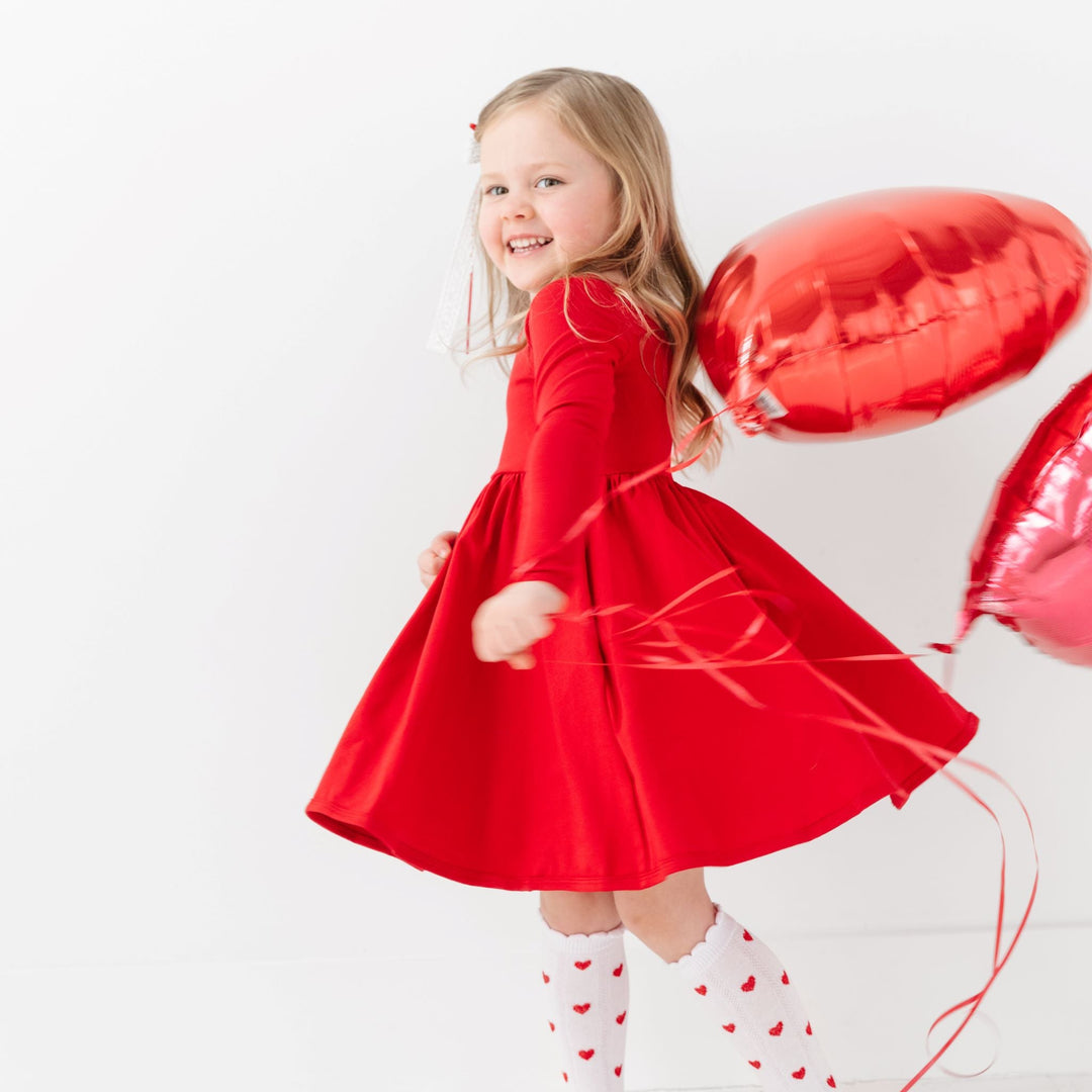 little girl twirling with heart balloons in red long sleeve twirl dress and red heart knee highs