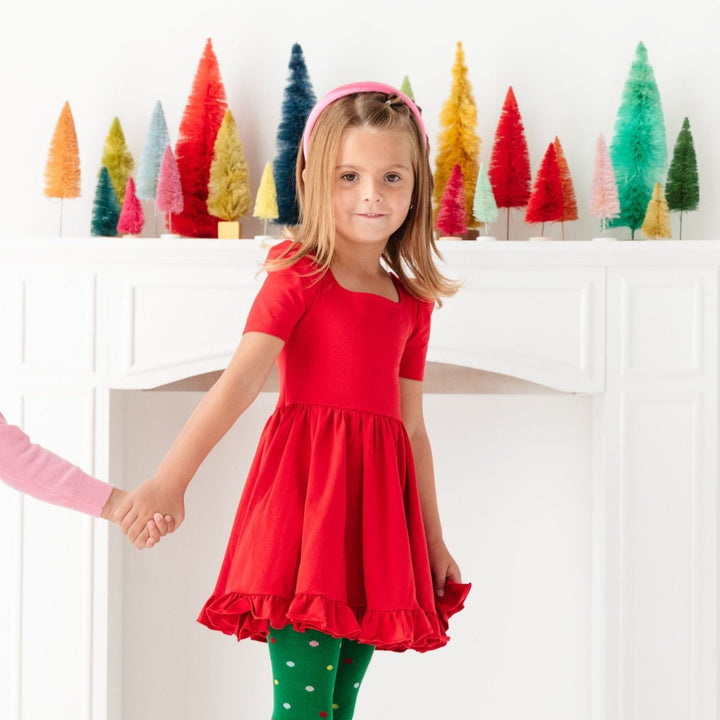 Little girl in red Christmas party dress, pink satin headband and matching tights with colorful polka dots