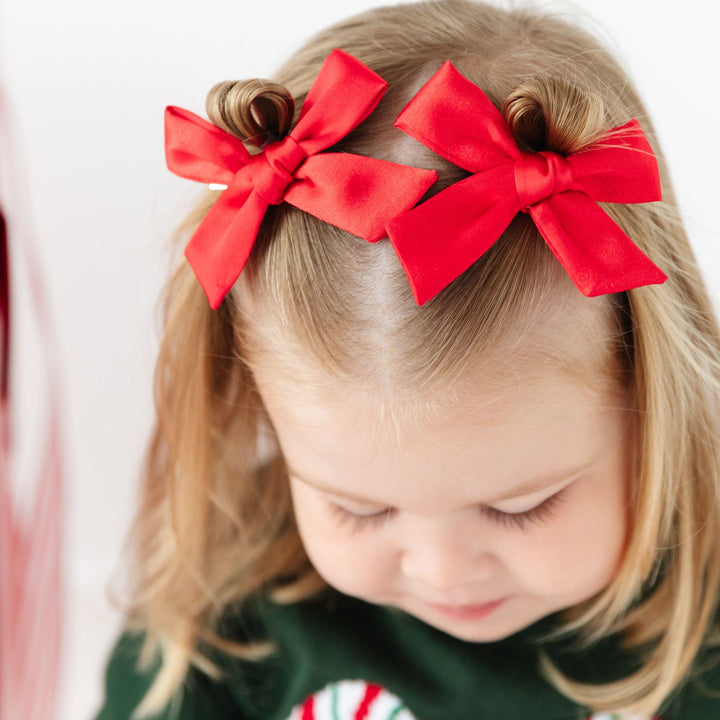 little girl in red satin bows and Christmas sweater