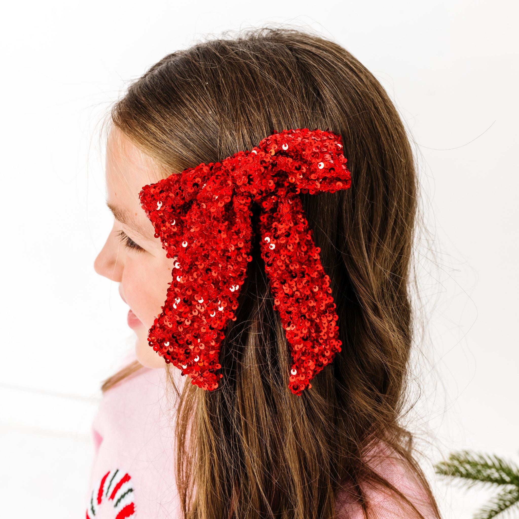 girl in red sequin bow on clip paired with pink candy cane sweater