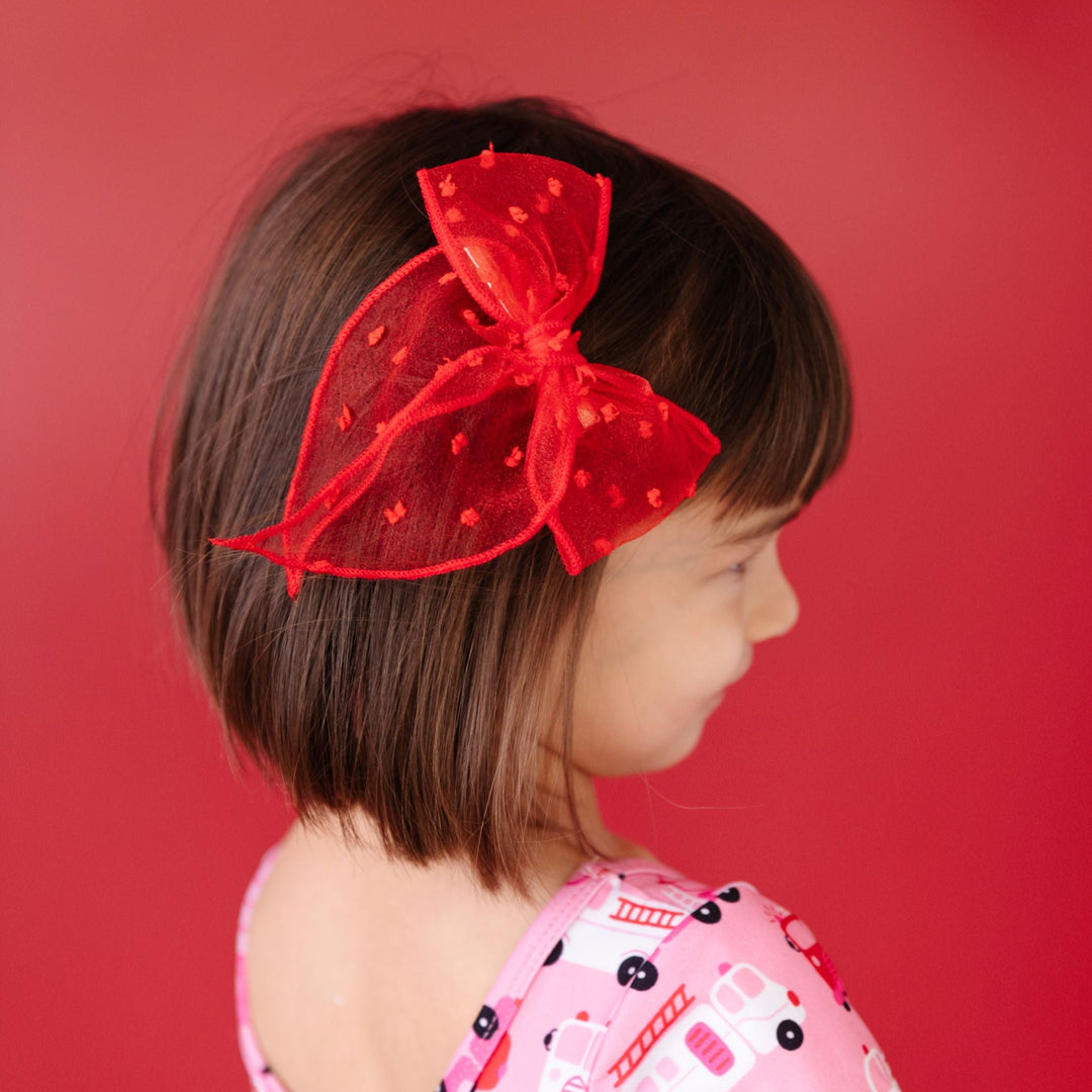 little girl in bright red sheer dot bow on clip and matching firetruck themed Valentine's print dress