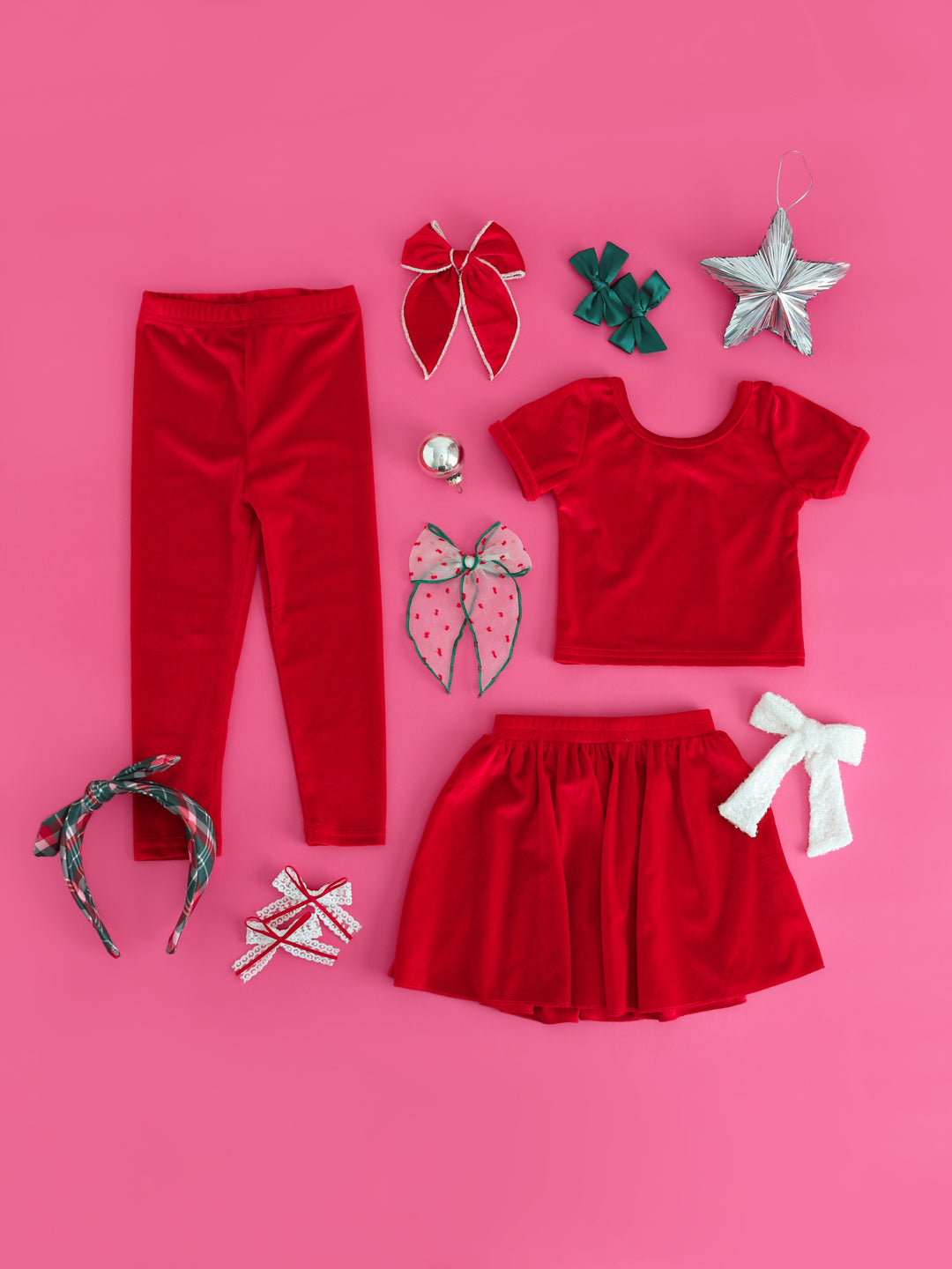 flat lay of bright red velvet charm top, leggings and skirt with matching hair accessories for Christmas