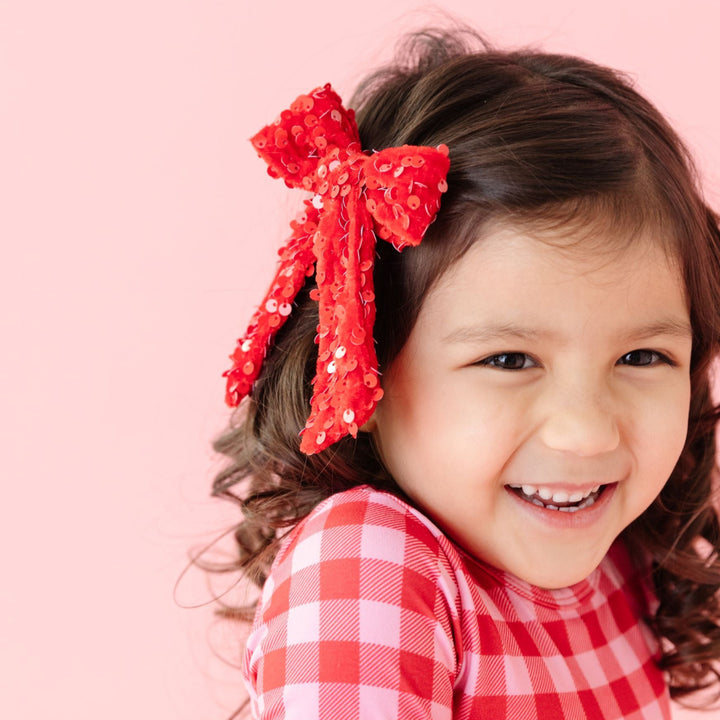 little girl in red velvet and sequin bow and matching valentine's day gingham dress