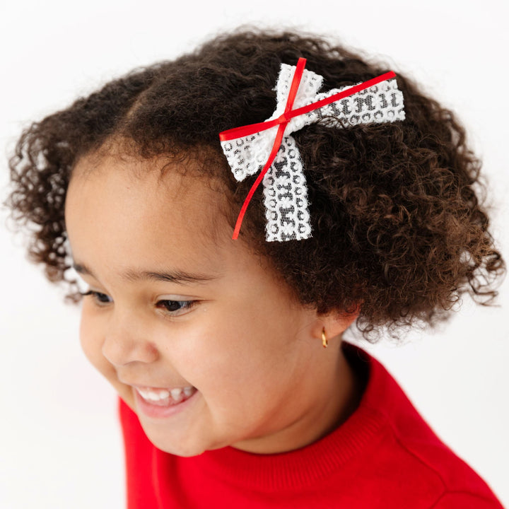 little girl in white lace pigtail bow with red satin ribbon and matching red sweater