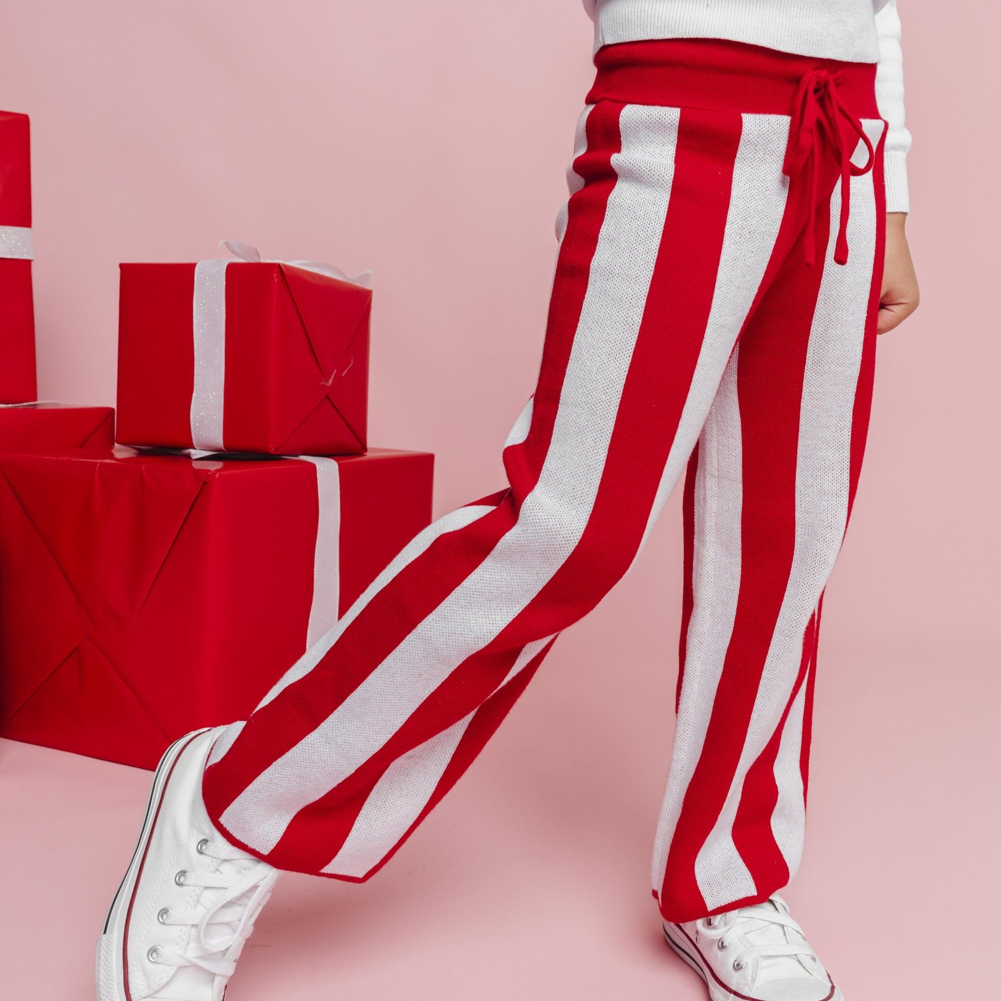 child in white Rudolph sweater with red and white striped sweater pants for Christmas