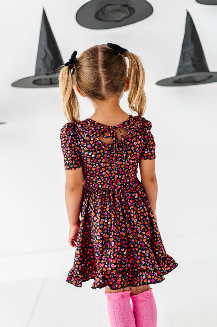 little girl facing away from camera to show tie back detail on black with pink and orange floral Halloween twirl dress