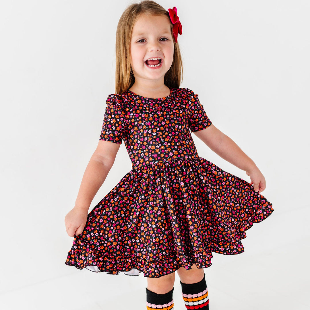 girl holding twirl dress in halloween flowers print