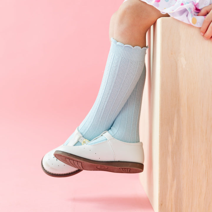 little girl sitting in pastel blue scalloped knee high socks with vertical knit pattern