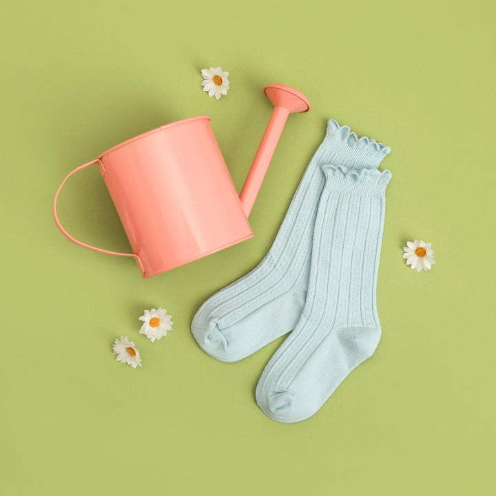 flay lay photo of girl's spring blue knee high socks with scalloped trim and watering can