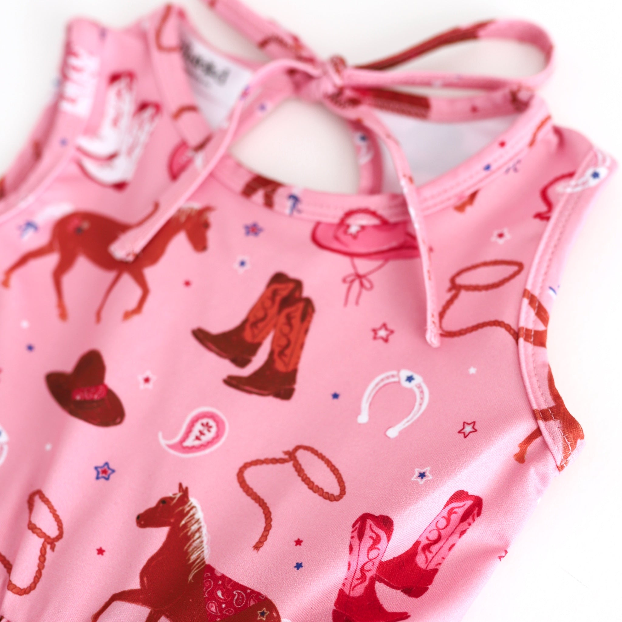 closeup of girls' pink tank dress with cowboy boots, horses and rodeo inspired details