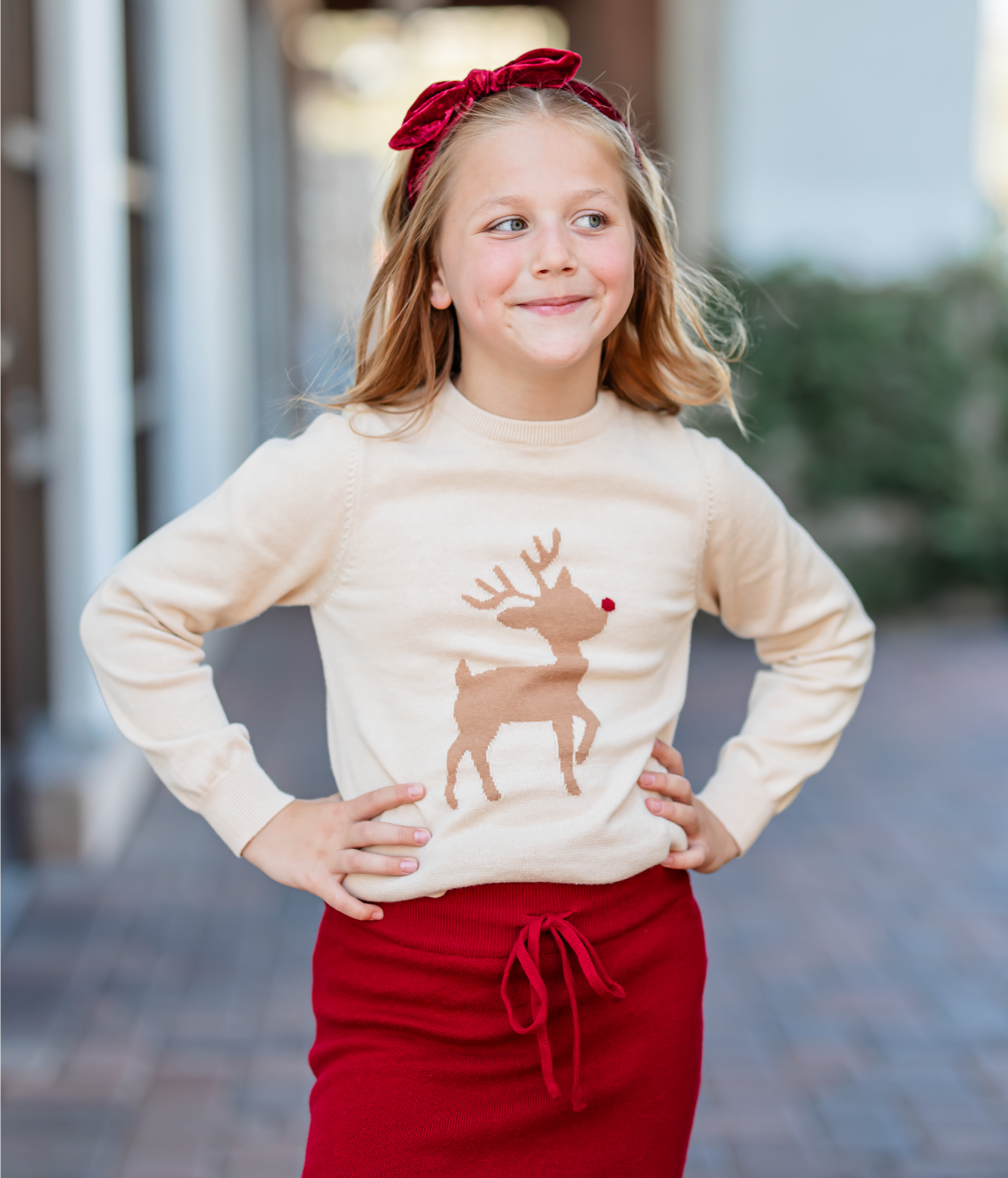 Little girl wearing vanilla reindeer knit sweater with crimson knit skirt and matching velvet headband