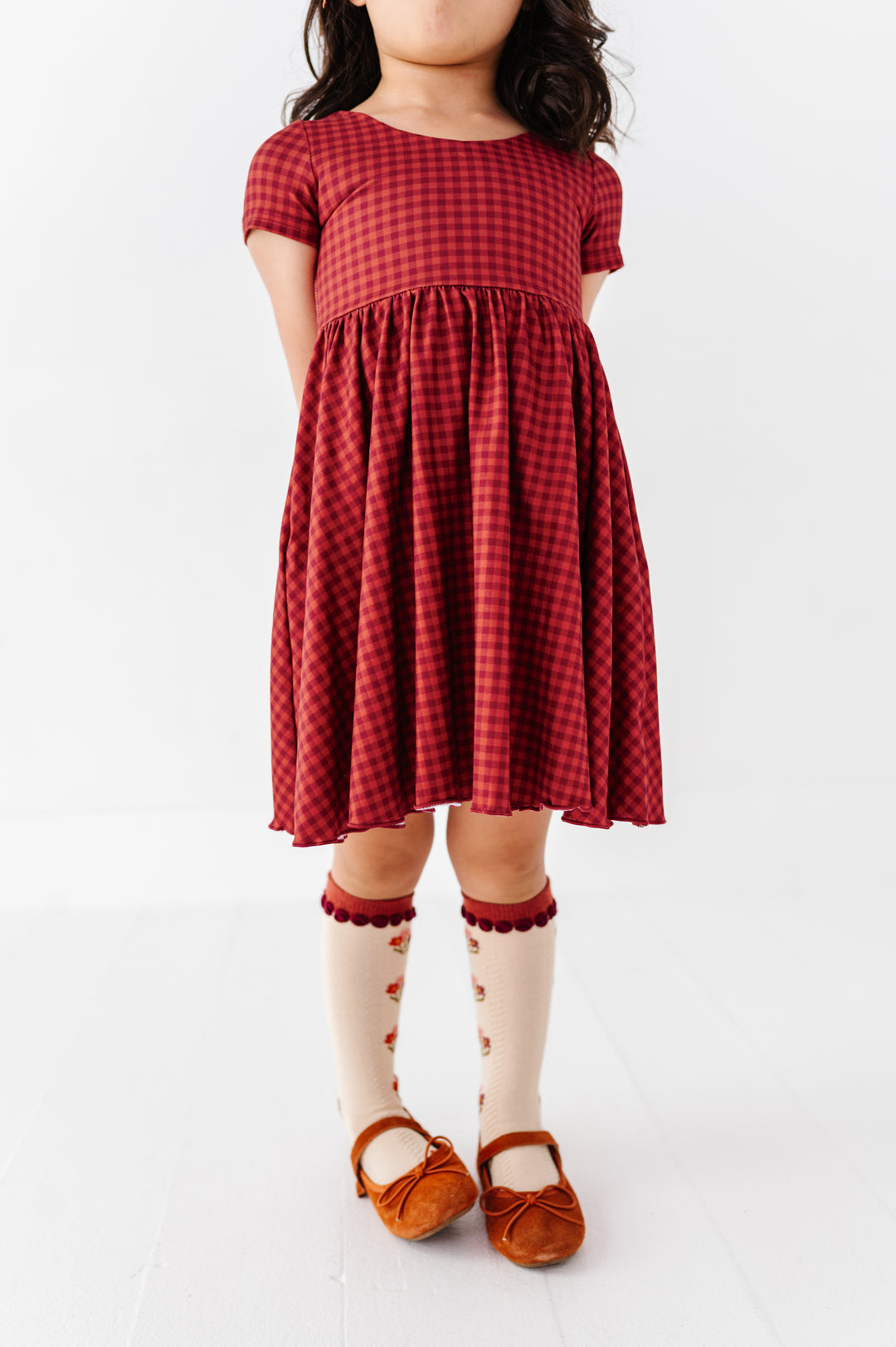 closeup of girl in rust and burgundy dress with matching bouquet knee highs