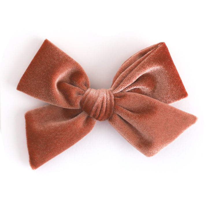 A fall rust velvet bow hair clip on a solid white background.